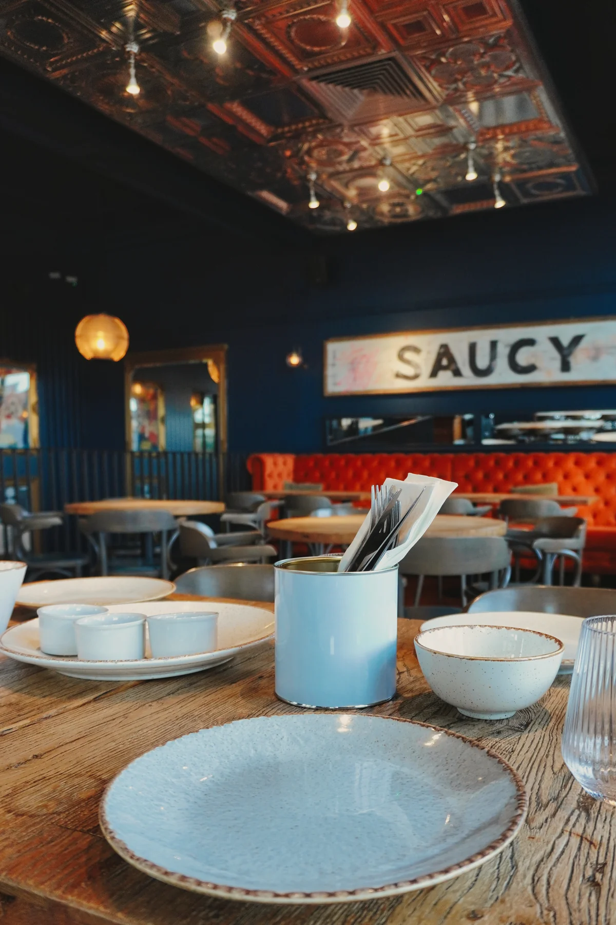 Set table facing the orange banquette and Saucy Bird sign