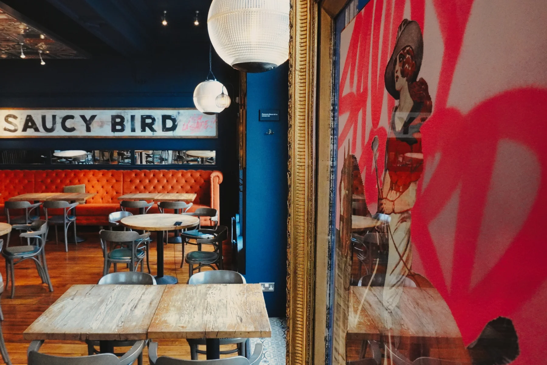 Restaurant tables beside framed Saucy Bird artwork