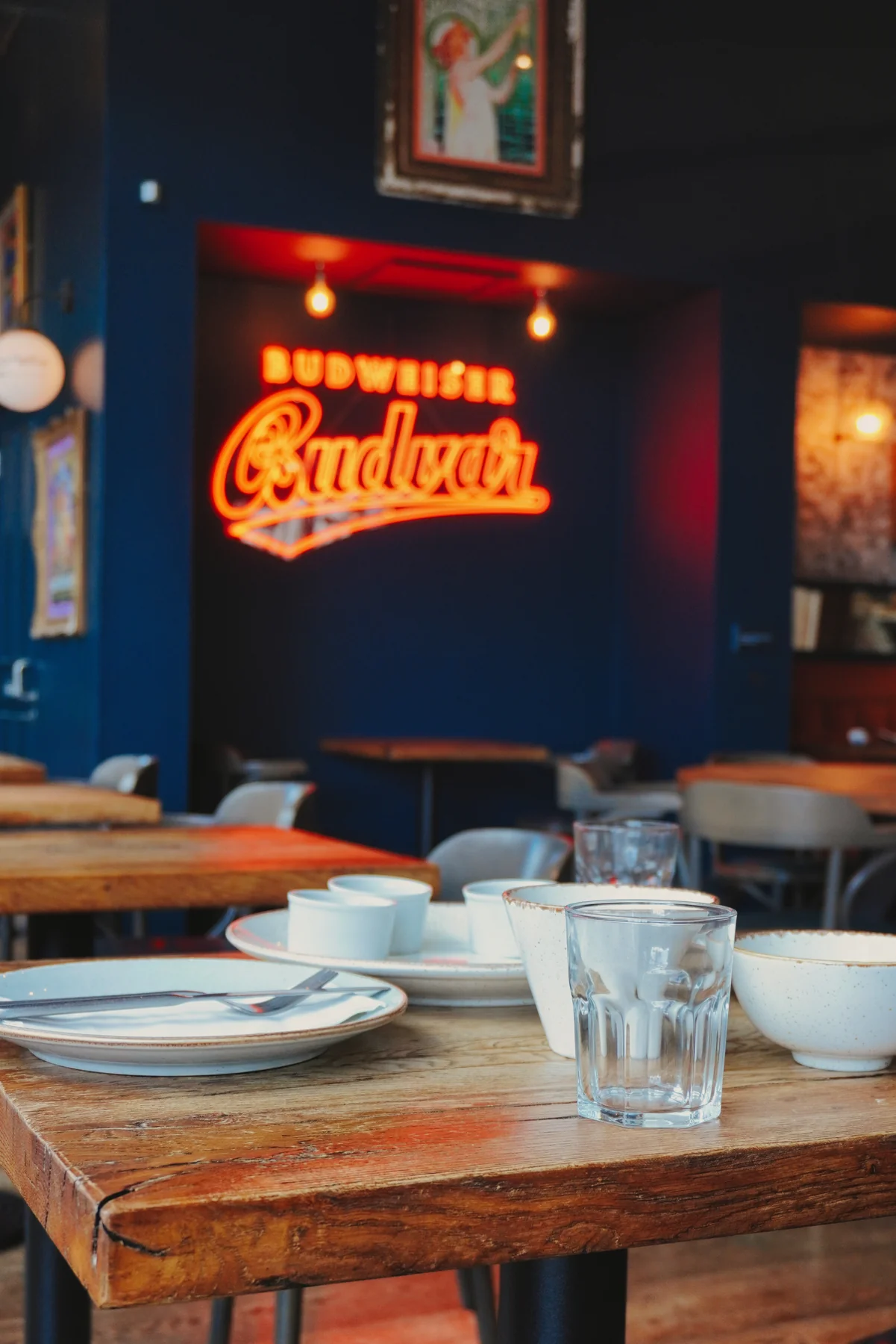 Wooden dining table below the illuminated brewery sign
